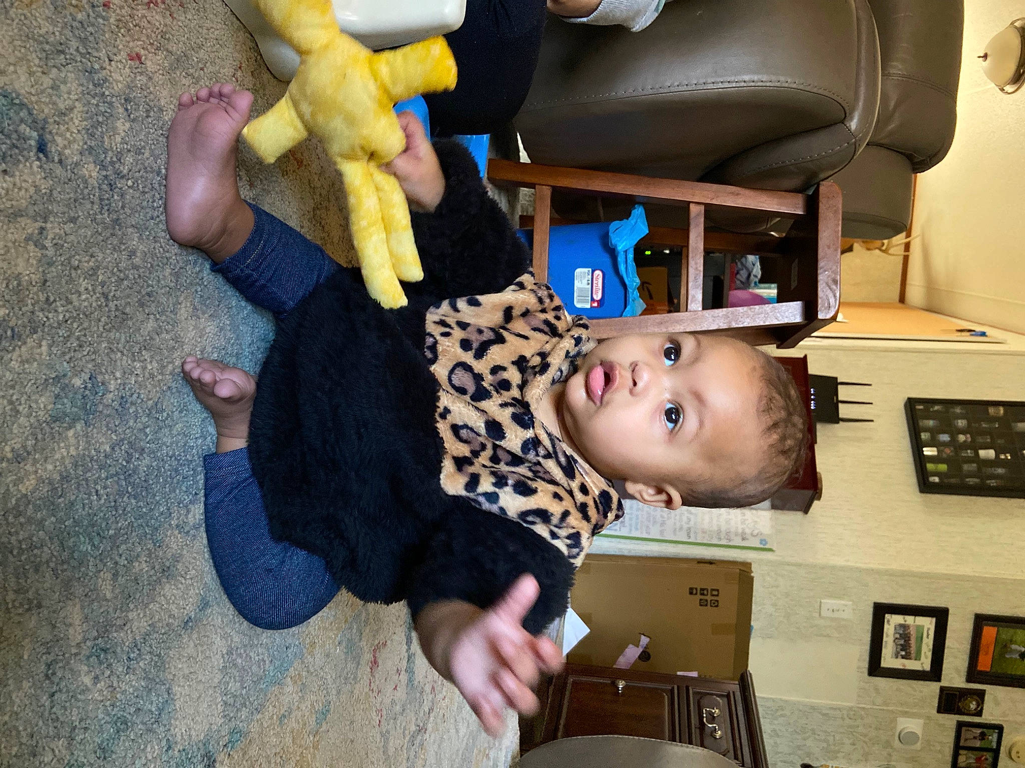 Maelynn is registered to the contest to win money with this photo: arm, baby, car_seat, chair, child, comfort, finger, fun, hand, happy, office_equipment, person, play, room, shelf, sitting, thumb, toddler, toy, tree