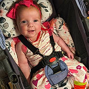 Rosemary is registered to the contest to win money with this photo: baby, child, smiling, stroller, headband, pink_bow, colorful_clothing, heart_pattern, striped_socks, floral_cushion, seatbelt, happy, indoor, toddler, cute, portrait, infant, clothing, person, seat