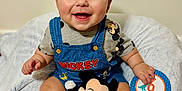 Atlas is registered to the contest to win money with this photo: baby, smiling, mickey_mouse, plush_toy, blanket, clothing, socks, milestone_card, indoor, child, happy, cute, portrait, seated, face, infant, toy, soft_texture, casual, playful