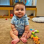 baby, child, infant, toys, carpet, shark_print, onesie, drool, playtime, floor, colorful, activity_gym, cute, indoors, sitting, smile, hand, foot, wooden_furniture, cushion