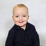 Frankie is registered to the contest to win money with this photo: toddler, child, smiling, blue_eyes, blond_hair, portrait, sweater, navy_clothing, happy, cute, face, young_child, studio_photo, innocent, light_background, casual_clothing, person, baby, headshot, friendly