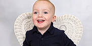 Frankie is registered to the contest to win money with this photo: child, toddler, smiling, happy, blue_eyes, short_hair, navy_shirt, buttoned_shirt, white_chair, woven_chair, portrait, studio, light_background, cute, young_child, sitting, indoors, face, person, joyful