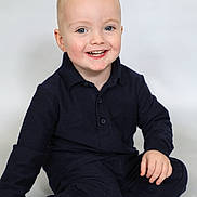 Frankie is registered to the contest to win money with this photo: toddler, child, smiling, blue_eyes, blonde_hair, sitting, navy_clothing, long_sleeves, pants, black_socks, studio_photo, portrait, happy, cute, indoor, isolated_background, young_child, casual_wear, face, person