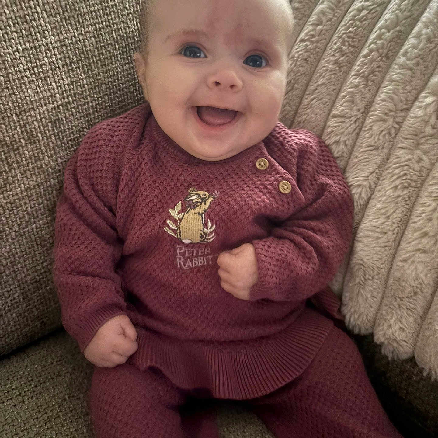 Lenie joined the competition — help win amazing prizes! baby, blanket, child, comfortable, couch, cozy, cute, face, furniture, happy, home_interior, infant, knitted_clothing, maroon_outfit, person, peter_rabbit, portrait, sitting, smiling, young_child