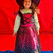 Angélina a rejoint le concours — aidez-le/la à gagner de superbes lots ! child, girl, costume, witch_hat, dress, smile, long_hair, standing, indoor, red_background, blue_floor, stars, purple, black, clothing, happy, portrait, holiday, celebration, childhood