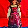 child, girl, costume, witch_hat, dress, smile, long_hair, standing, indoor, red_background, blue_floor, stars, purple, black, clothing, happy, portrait, holiday, celebration, childhood