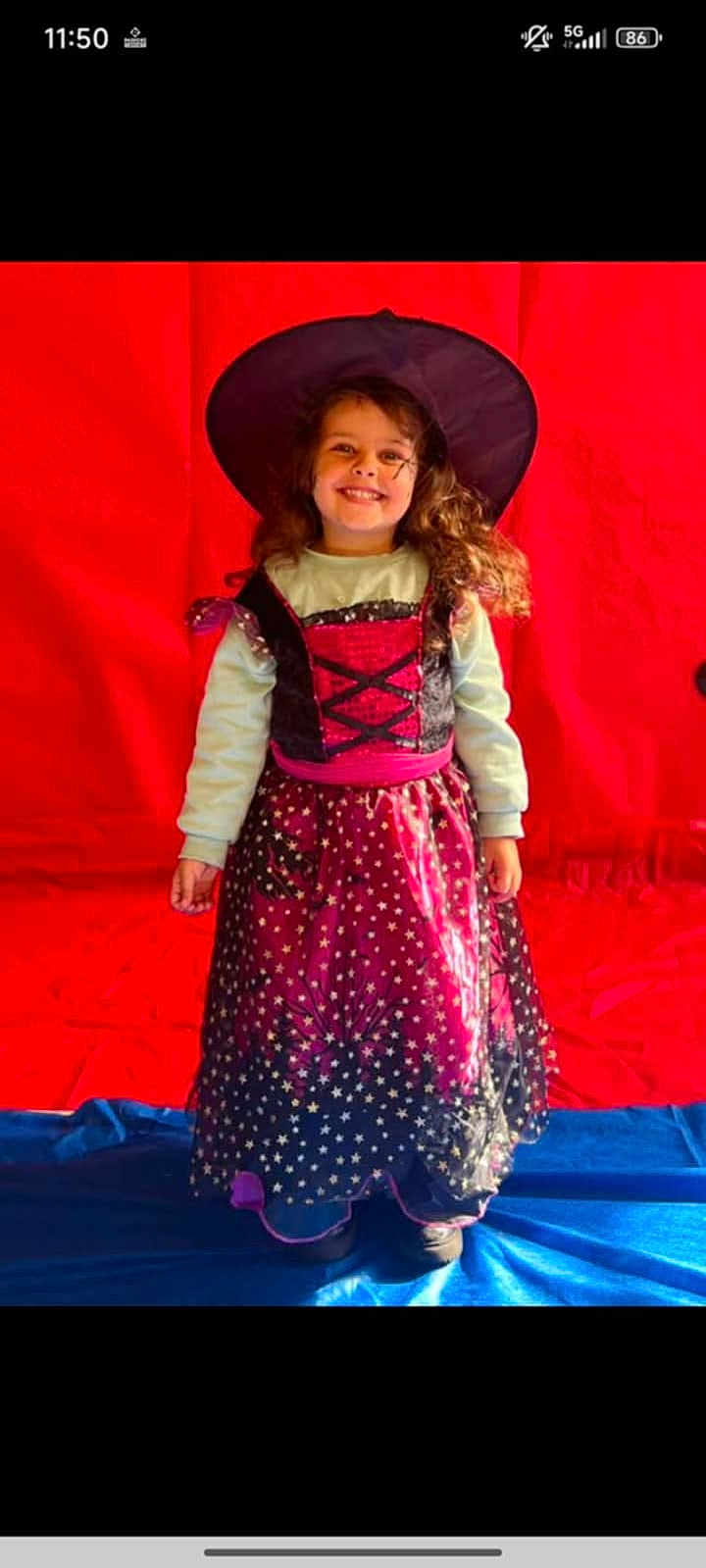 Angélina a rejoint le concours — aidez-le/la à gagner de superbes lots ! child, girl, costume, witch_hat, dress, smile, long_hair, standing, indoor, red_background, blue_floor, stars, purple, black, clothing, happy, portrait, holiday, celebration, childhood