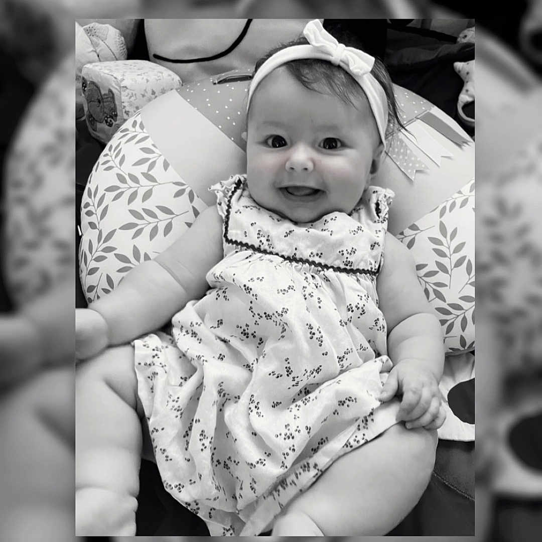 Bianka a rejoint le concours — aidez-le/la à gagner de superbes lots ! baby, black_and_white, child, clothing, comfortable, cushion, cute, dress, face, happy, head, headband, indoors, infant, pattern, person, portrait, sitting, smiling, young