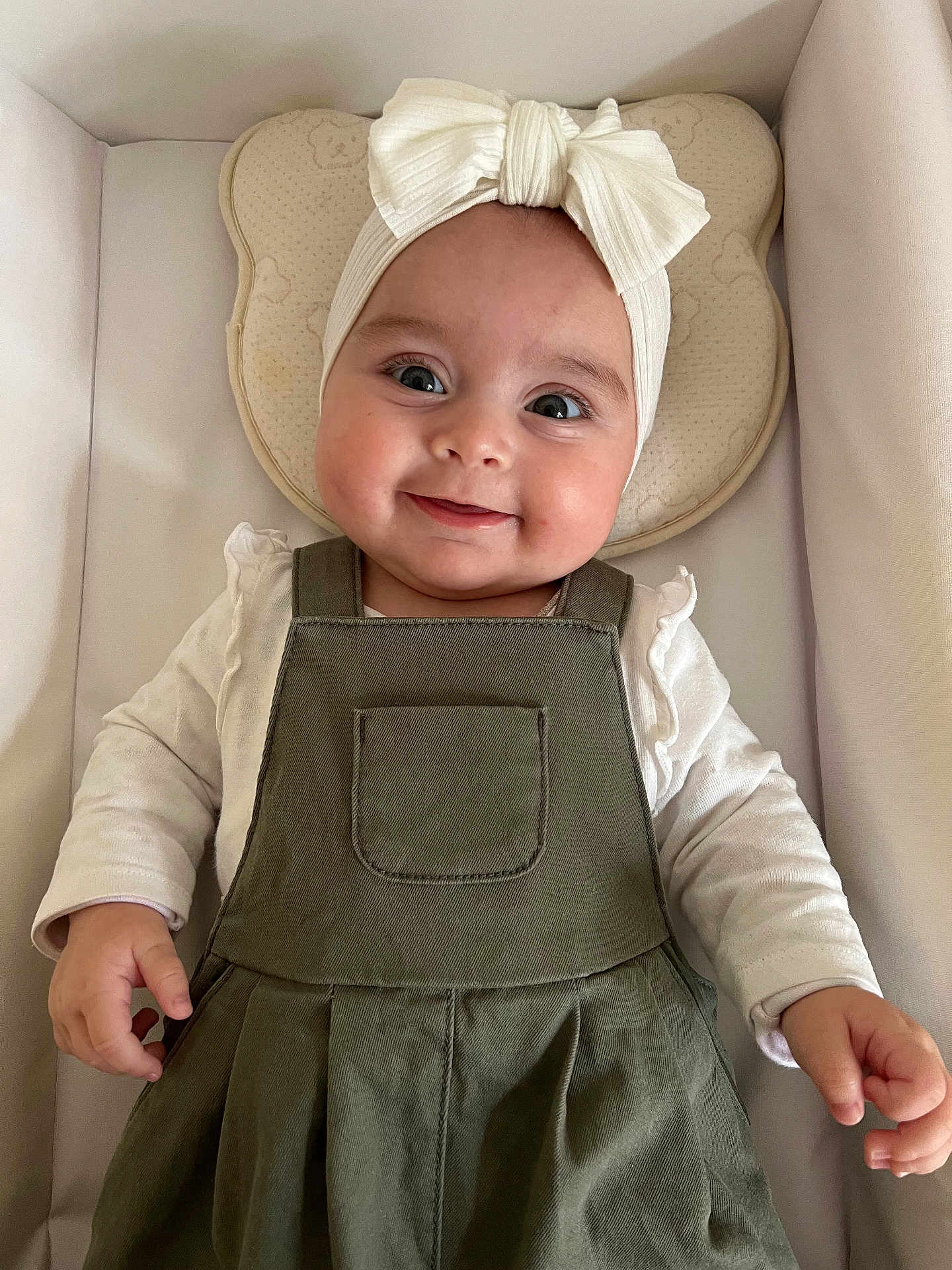 Juliana a rejoint le concours — aidez-le/la à gagner de superbes lots ! baby, smiling, headband, bow, green_dress, infant, cushion, bear_shape, white_shirt, lying_down, cute, child, portrait, indoors, happy, person, small_hands, soft_lighting, cozy, clothing