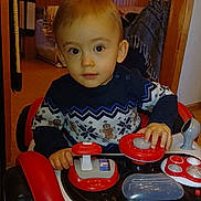 Martin a rejoint le concours — aidez-le/la à gagner de superbes lots ! blanket, buttons, child, curious, doorway, eyes, face, floor, furniture, hands, indoor, patterned_clothing, play, room, seat, steering_wheel, sweater, toddler, toy_car, young_child