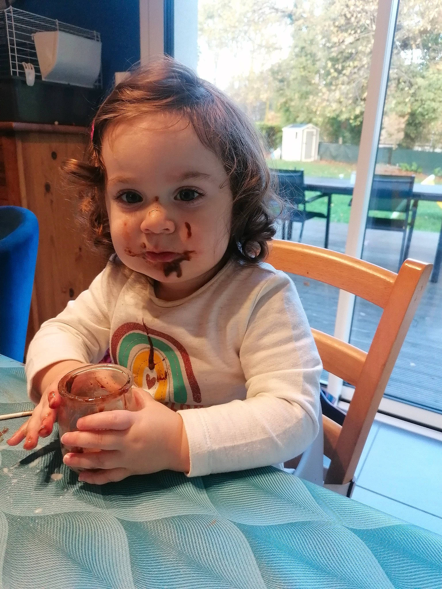 Lola participe au concours pour gagner de l'argent avec cette photo : chair, child, eye, face, facial_expression, flooring, fun, hairstyle, happy, iris, leisure, person, plant, sitting, skin, table, tableware, thumb, toddler, tree