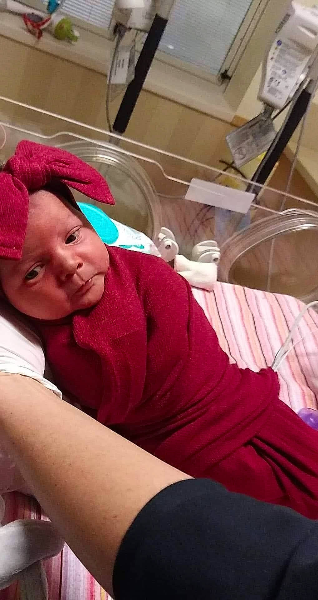 Ashlynn is registered to the contest to win money with this photo: baby, baby_toddler_clothing, cap, car_seat, carmine, comfort, elbow, human_body, human_leg, knee, lap, leisure, magenta, person, room, shorts, sitting, smile, t_shirt, thigh