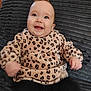 baby, black_pants, blanket, blue_eyes, child, clothing, cute, face, furniture, happy, indoor, infant, leopard_print, person, portrait, sitting, smiling, sweater, texture, young_child