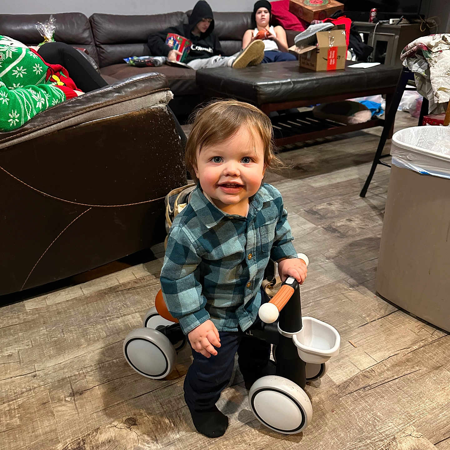 Emmett joined the competition — help win amazing prizes! beanie, cardboard_box, child, couch, family, flooring, furniture, happy, hoodie, indoor, living_room, person, plaid_shirt, ride_on_toy, smile, socks, television, toddler, toy, wood_floor