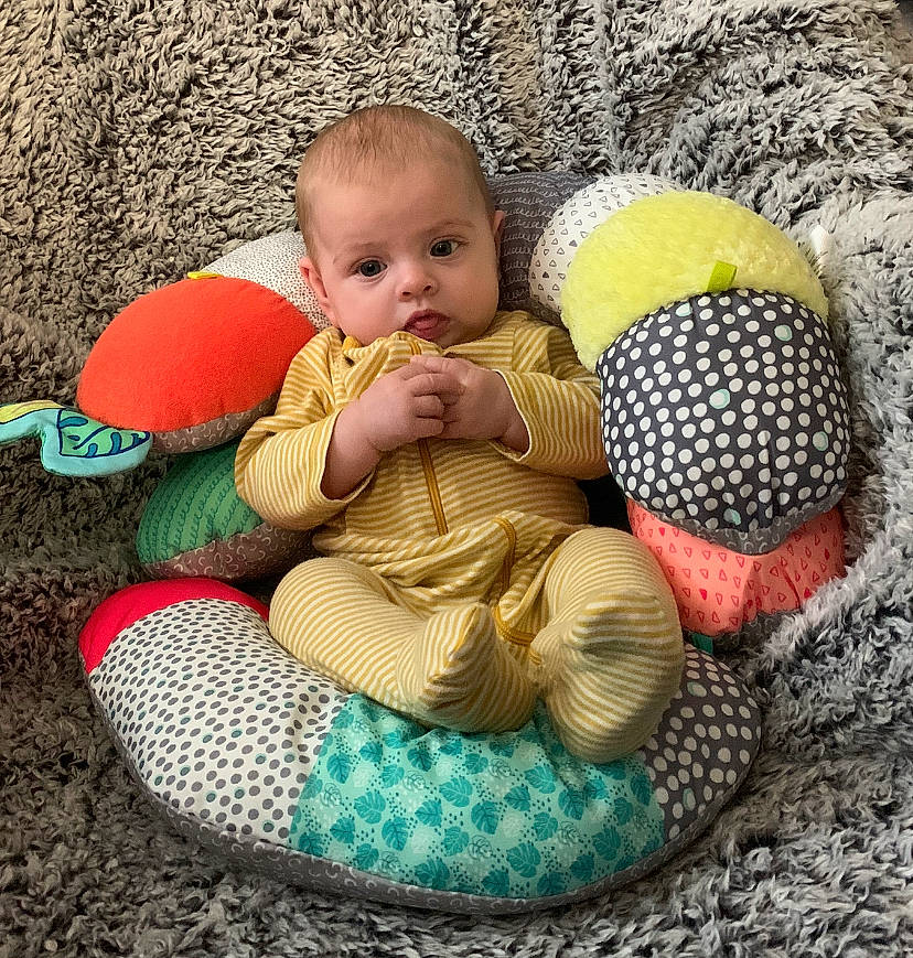 Clementine is registered to the contest to win money with this photo: baby, baby_products, baby_toddler_clothing, comfort, eye, finger, grass, hand, head, headgear, leg, person, product, shoe, sitting, skin, stuffed_toy, sun_hat, toddler, toy