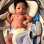 baby, infant, diaper, curly_hair, face, skin, blanket, baby_seat, cushion, straps, indoors, child, newborn, cute, resting, portrait, soft, comfort, fist, expression