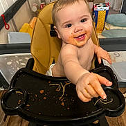 Bowen is registered to the contest to win money with this photo: baby, high_chair, food, spaghetti, messy, indoor, playpen, child, smiling, face, hand, diaper, floor, wooden_floor, background, toy, seat, person, happy, reaching