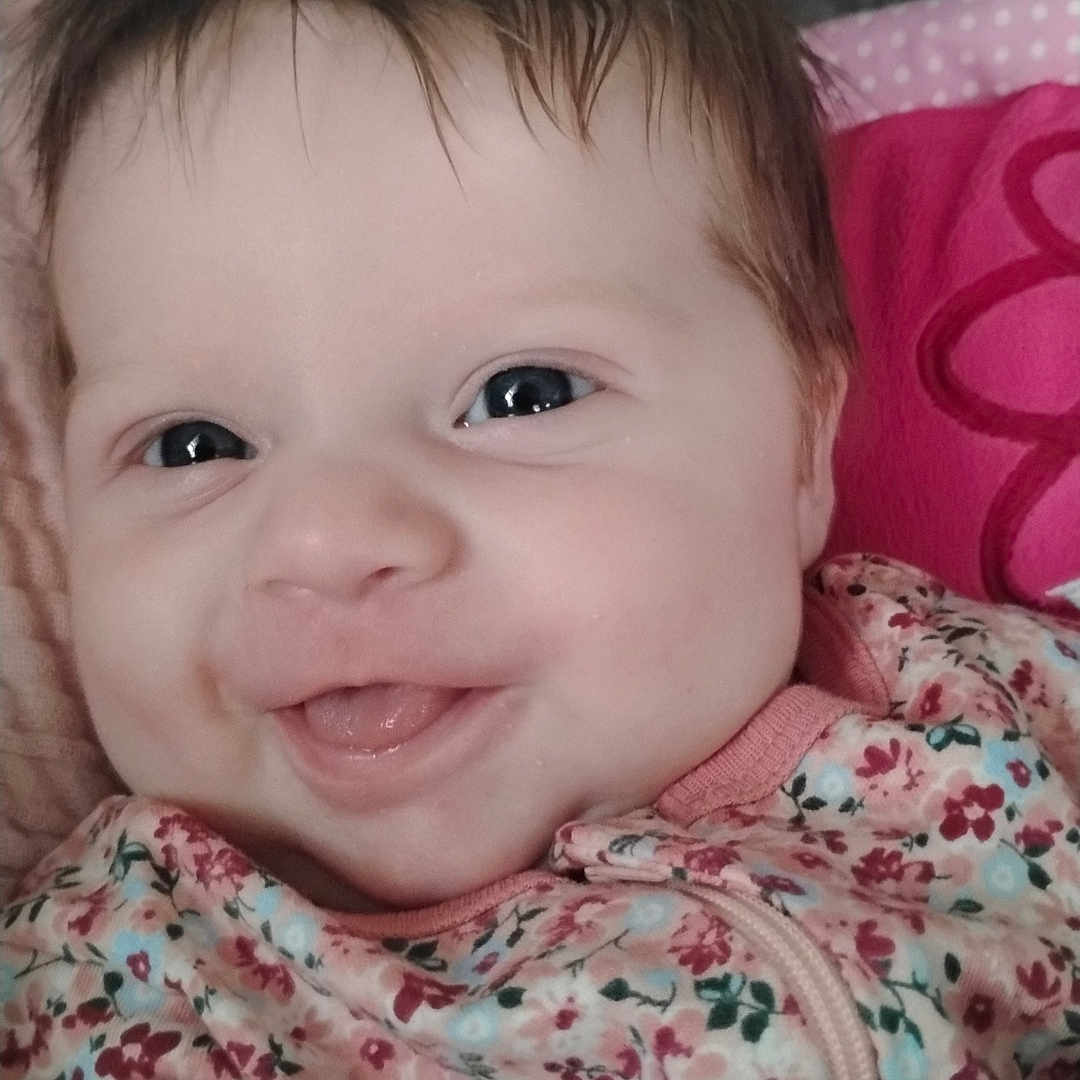 Alazea is registered to the contest to win money with this photo: baby, blue, child, close_up, clothing, cute, expression, eyes, face, floral_pattern, happy, head, indoors, infant, pink, portrait, skin, smiling, soft_texture, young_child