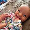 Mckinleigh is registered to the contest to win money with this photo: baby, infant, child, smiling, happy, portrait, face, eyes, floral_clothing, onesie, bed, blanket, bedroom, indoor, adult_hand, cuddling, close_up, gummy_smile, cozy, photography