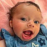 Mckinleigh is registered to the contest to win money with this photo: baby, infant, child, portrait, smiling, laughing, open_mouth, blue_eyes, curly_hair, facial_expression, close_up, indoor, blanket, pink_background, blue_clothing, embroidered_clothing, sitting, happy, baby_portrait, cozy
