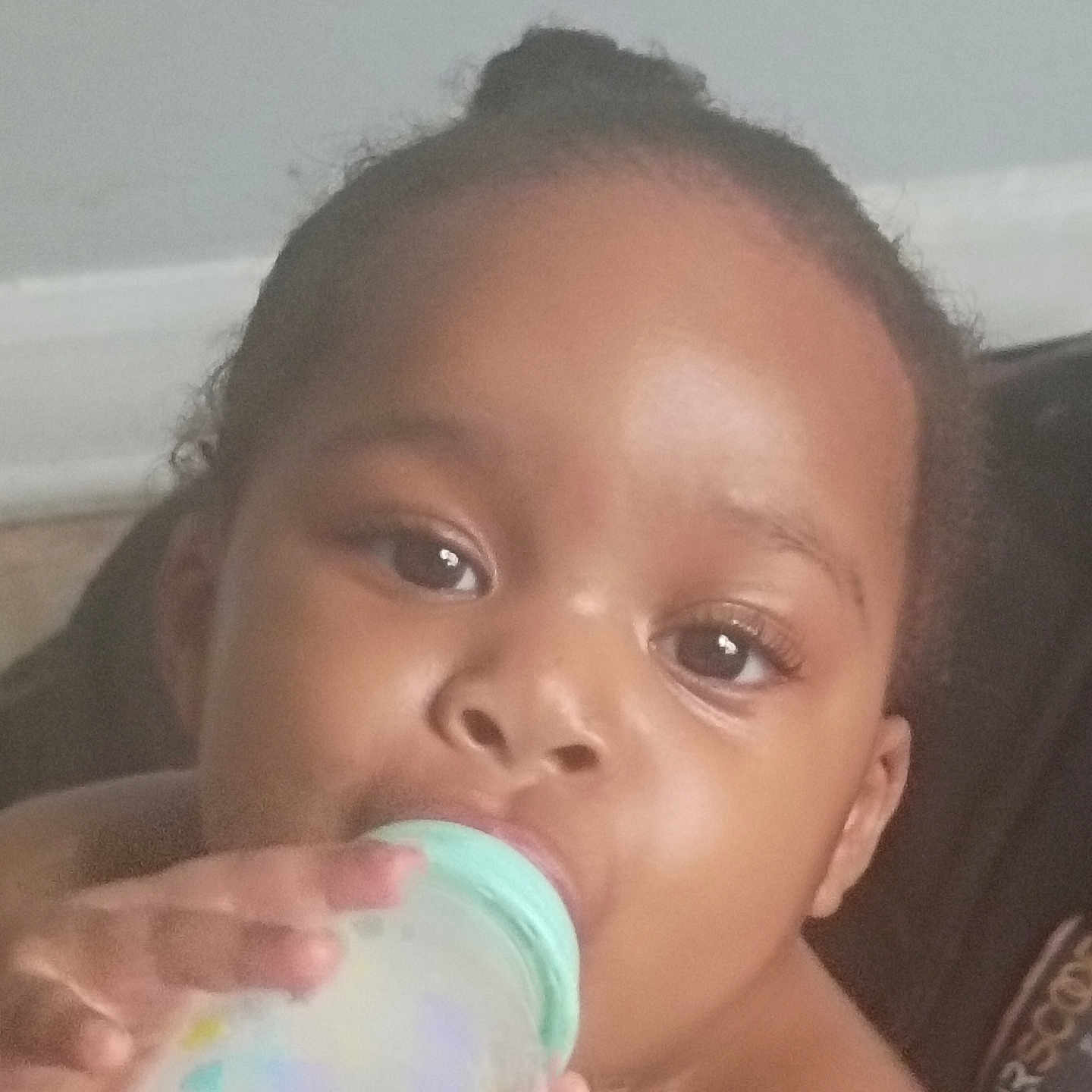 Lilah joined the competition — help win amazing prizes! baby, bottle, child, closeup, curious, cute, drinking, expression, eyelashes, face, feeding, hand, head, indoors, infant, person, portrait, sitting, skin, young