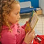 Adixia a rejoint le concours — aidez-le/la à gagner de superbes lots ! child, girl, reading, book, curly_hair, braids, pink_hoodie, red_skirt, couch, indoor, floor_tiles, blue_wall, space_mural, seated, profile_view, focus, leisure, education, young, casual_clothing