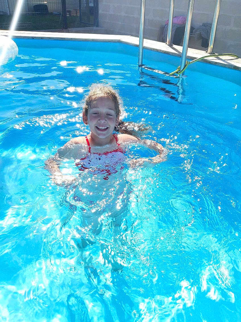 Adixia a rejoint le concours — aidez-le/la à gagner de superbes lots ! child, pool, water, swimming, sunlight, smile, outdoor, summer, fun, recreation, happy, swimsuit, reflection, sparkle, ladder, fence, backyard, leisure, person, blue
