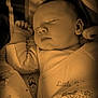 baby, sleeping, pajamas, cartoon_characters, blanket, infant, cute, peaceful, face, hand, closed_eyes, child, soft_light, bedtime, portrait, cozy, toddler, indoor, clothing, sleep