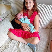 Maëwen a rejoint le concours — aidez-le/la à gagner de superbes lots ! baby, baby_holding, blanket, blue_outfit, bracelet, child, couch, cozy, cross_legged, expression, family, girl, hair, indoor, living_room, newborn, red_dress, seated, skin, smile