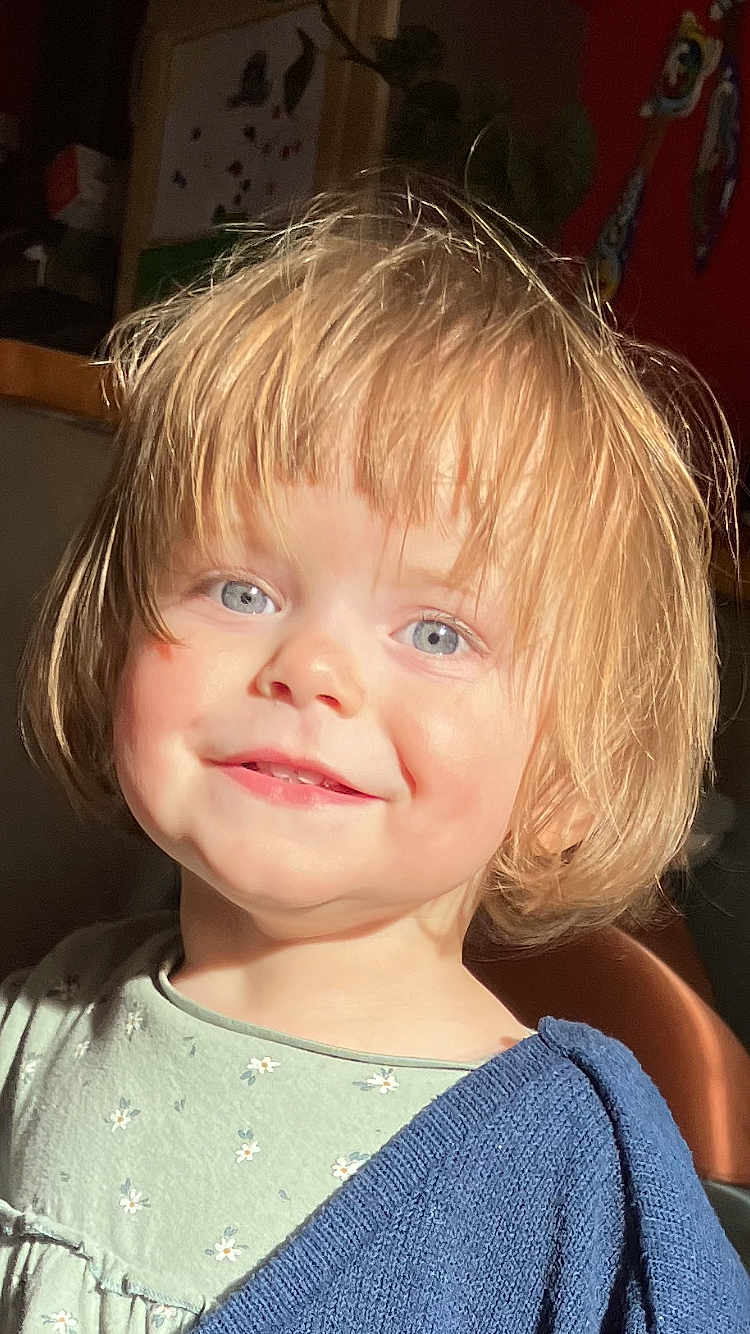 Cylia participe au concours pour gagner de l'argent avec cette photo : child, toddler, smile, blond_hair, blue_eyes, face, portrait, sunlight, rosy_cheeks, clothing, sweater, dress, indoors, cute, happy, young_child, person, headshot, expression, natural_light