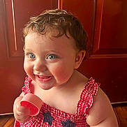 Collins joined the competition — help win amazing prizes! baby, child, smiling, blue_eyes, curly_hair, red_dress, checkered_pattern, holding_object, pink_cup, indoor, wooden_door, happy, cute, portrait, infant, close_up, cheerful, playful, skin, person