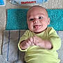 baby, infant, diapers, towel, yellow_shirt, smiling, tongue_out, baby_wipes, cute, lying_down, playful, child, skin, person, floor, expression, happy, newborn, clothing, indoors