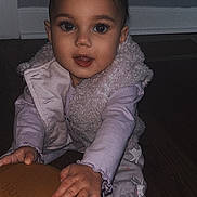 Naomi is registered to the contest to win money with this photo: toddler, child, baby, pajamas, vest, floor, wooden_floor, container, lid, hand, face, eyes, indoor, curious, happy, cozy_clothing, home, crawling, sitting, young_child