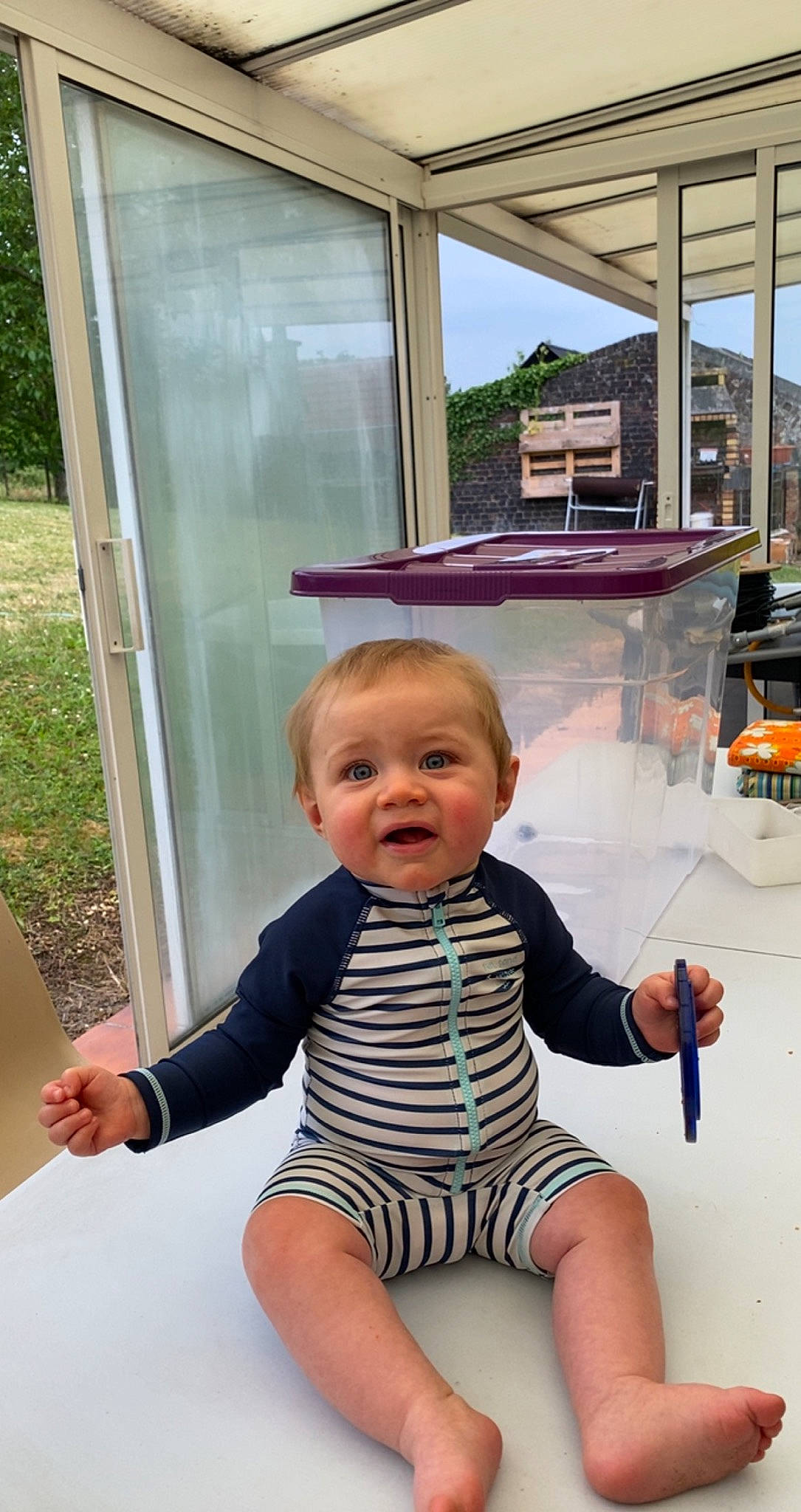 Emillio participe au concours pour gagner de l'argent avec cette photo : baby, baby_toddler_clothing, child, finger, flooring, fun, gesture, hairstyle, happy, human_leg, leisure, person, shade, shoulder, sitting, sky, sleeve, t_shirt, thumb, toddler