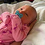 baby, pacifier, pink_clothing, flamingo_pattern, blanket, hand, newborn, cute, sleepwear, indoor, person, infant, soft, resting, cozy, head, face, lying_down, comfort, toddler