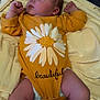 baby, sleeping, infant, onesie, flower_print, yellow_clothing, blanket, soft_fabric, peaceful, newborn, lying_down, indoors, cute, chubby_legs, closed_eyes, hand_fist, cozy, portrait, child, resting