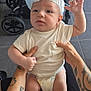 baby, blue, chair, curious, diaper, expression, floor, foot, hands, headwear, holding, indoor, infant, leg, person, skin, stroller, tattoo, white, white_shirt