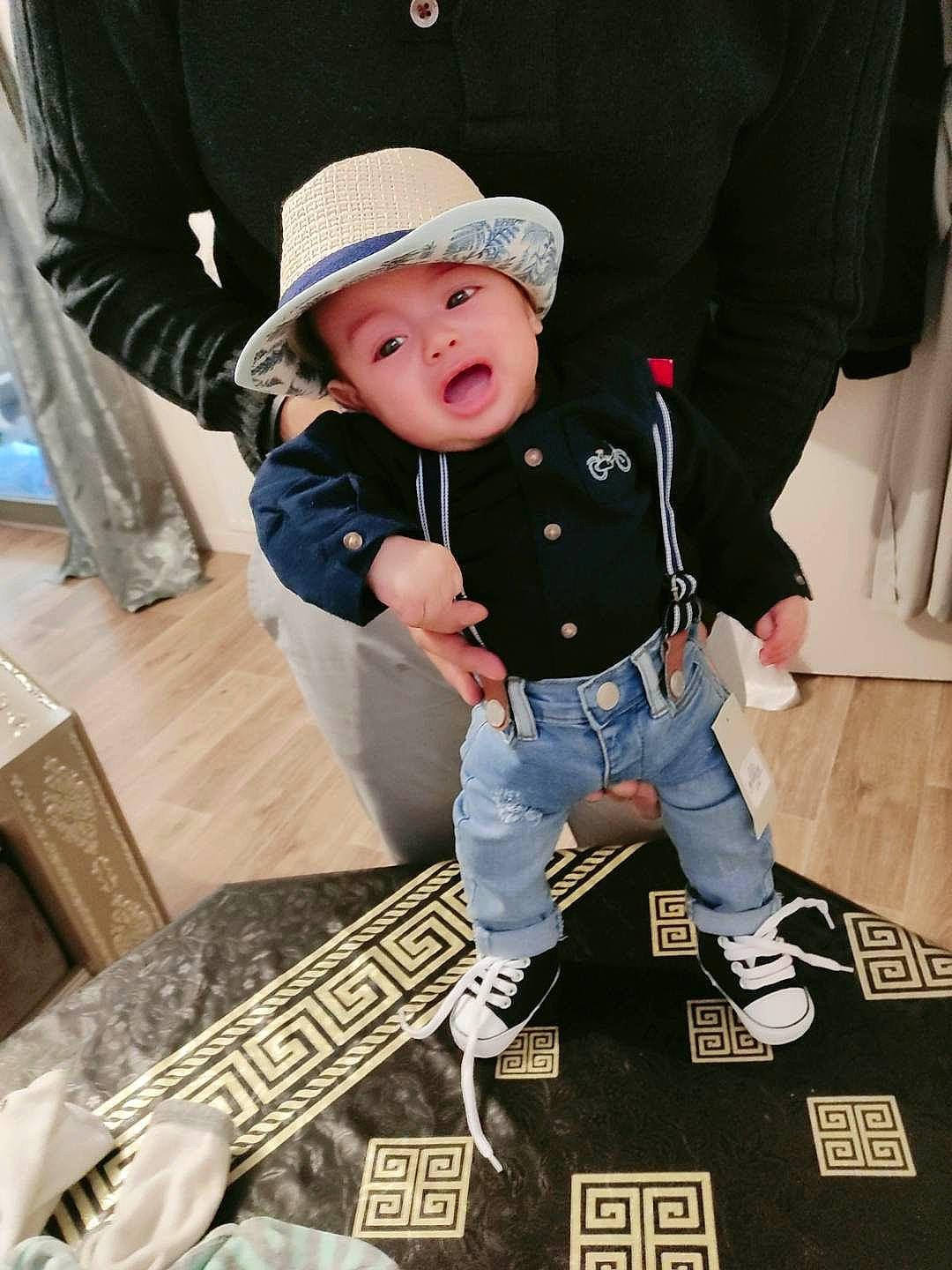 Tariq participe au concours pour gagner de l'argent avec cette photo : baby, baby_toddler_clothing, baseball_cap, cap, child, fashion_accessory, flooring, fun, hat, headgear, headwear, leisure, pattern, person, recreation, sitting, sleeve, smile, sun_hat, surprise