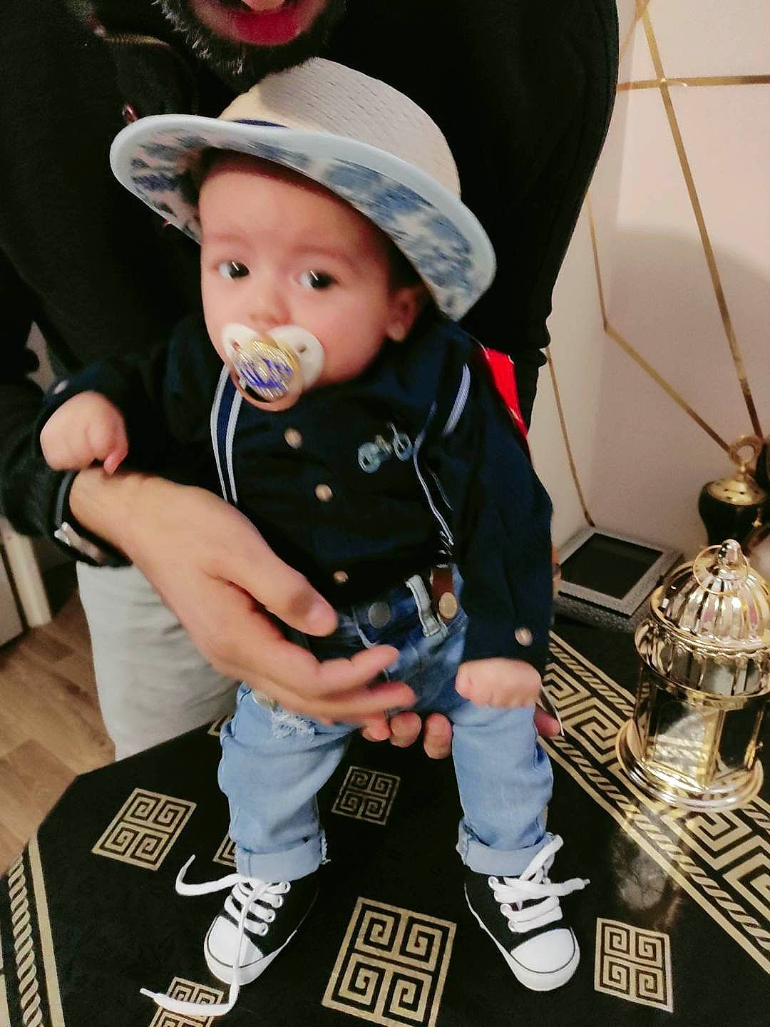 Tariq participe au concours pour gagner de l'argent avec cette photo : baby, baby_carriage, baby_toddler_clothing, baseball_cap, black, cap, carmine, child, cool, costume_hat, event, face, fashion_accessory, fedora, fun, hat, headwear, person, smile, sun_hat