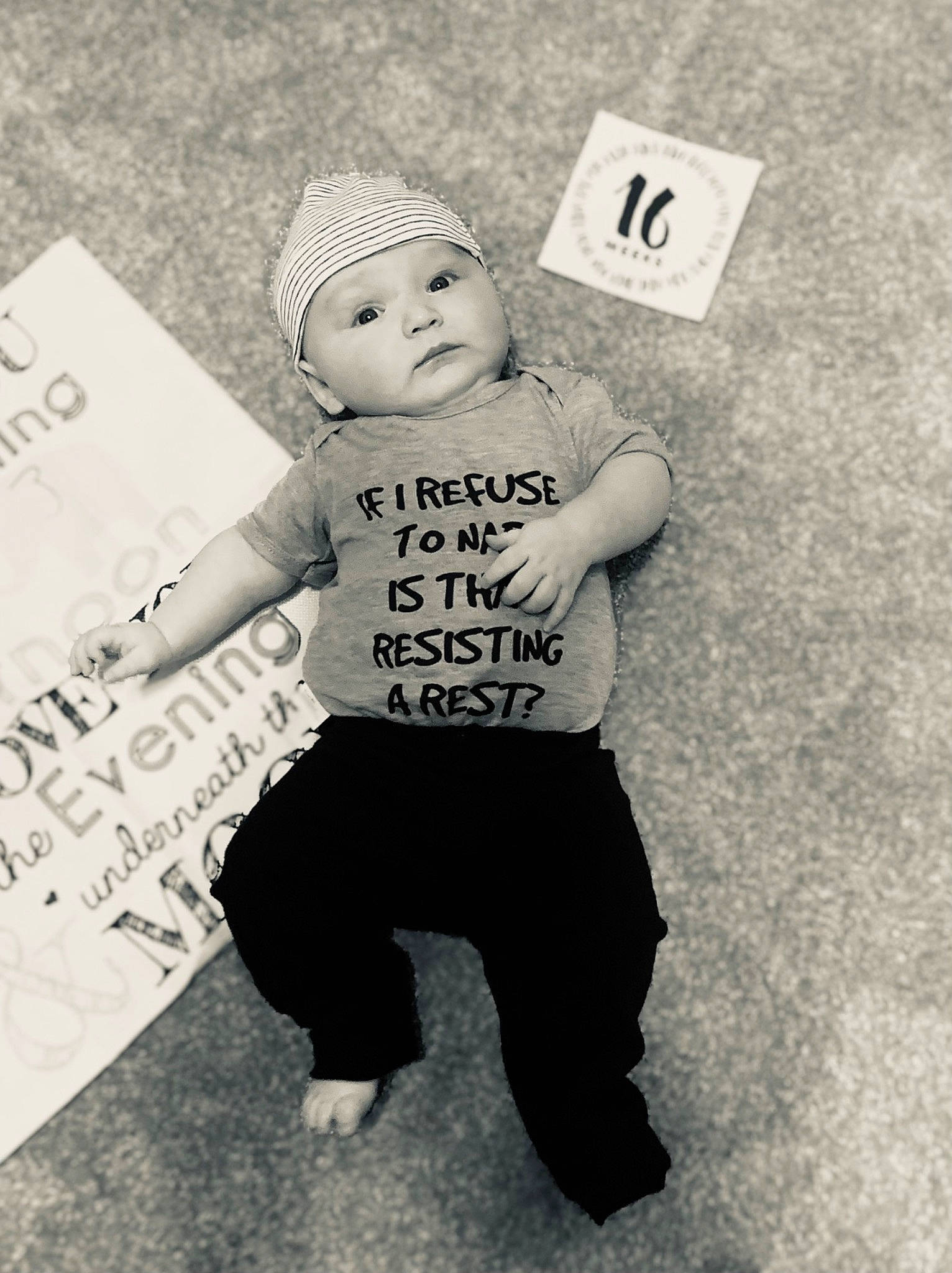 Jayden is registered to the contest to win money with this photo: arm, baby, baby_toddler_clothing, black_and_white, cap, child, costume_hat, fashion_accessory, flash_photography, font, gesture, hand, happy, headwear, monochrome, monochrome_photography, person, sleeve, style, t_shirt