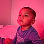 Nehemiah is registered to the contest to win money with this photo: toddler, child, portrait, indoor, bed, pink_light, casual_clothing, curious, face, eyelashes, short_hair, sitting, wall, pillow, blue_shirt, young_child, skin, expression, room, soft_lighting