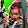 Naleighna is registered to the contest to win money with this photo: baby, child, car_seat, red_bow, plush_toy, minnie_mouse, pink_blanket, green_background, wide_eyes, curious, infant, clothing, seatbelt, portrait, indoor, cute, toy, face, person, young