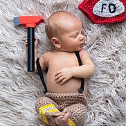 Callum joined the competition — help win amazing prizes! baby, newborn, infant, sleeping, toy_hammer, firefighter_hat, crochet_hat, fur_rug, blanket, bare_chest, crochet_pants, hand, feet, portrait, soft_lighting, closeup, props, cute, peaceful, studio_photo