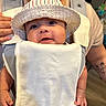 Oliver joined the competition — help win amazing prizes! baby, infant, baby_carrier, hat, striped_hat, person, adult, hand, face, smile, indoor, clothing, white_clothing, skin, tattoo, babywearing, parent, closeup, cute, child