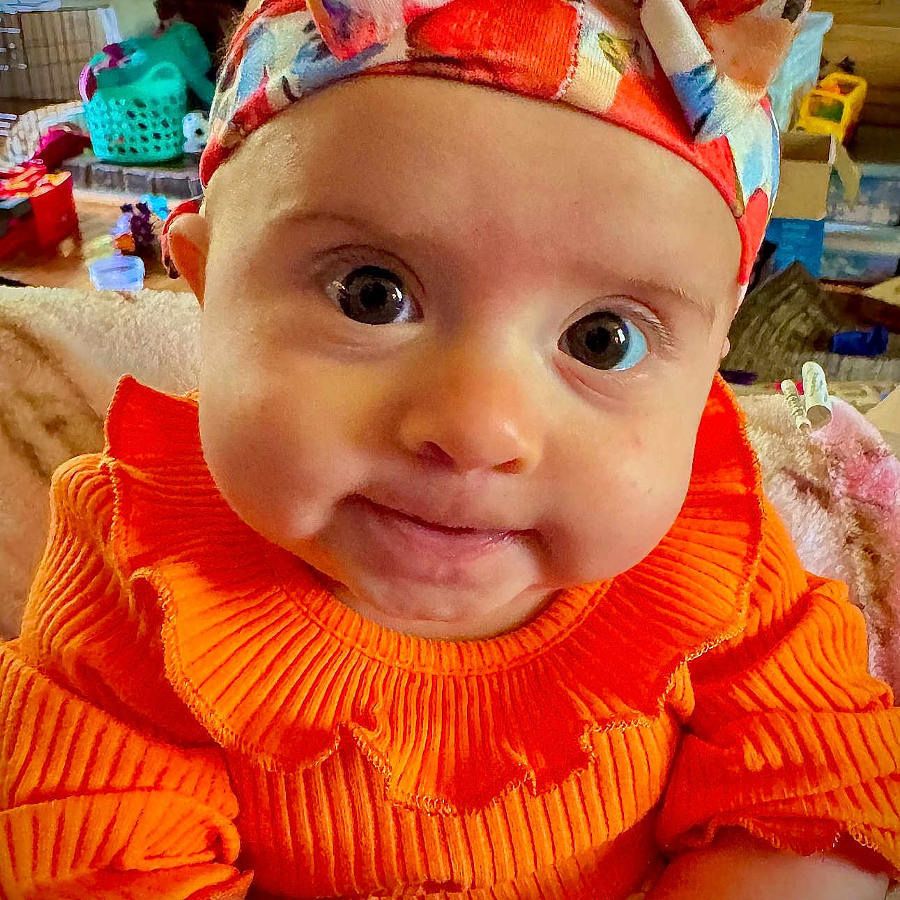 Rosemary is registered to the contest to win money with this photo: baby, casual, child, closeup, colorful, cozy, curious, cute, expression, face, hands, headband, indoor, infant, living_room, orange_clothing, portrait, ribbed_sweater, soft_lighting, young_child