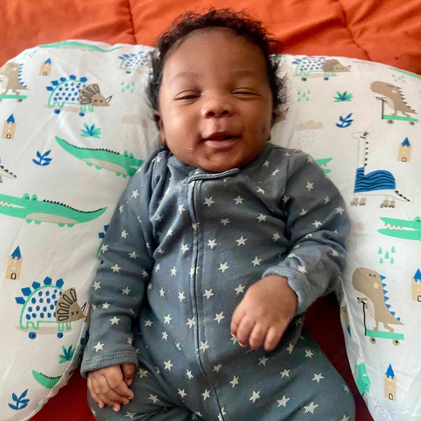 Kalvary joined the competition — help win amazing prizes! baby, child, cozy, curly_hair, cute, dinosaur_pattern, happy, indoors, infant, lying_down, onesie, orange_blanket, pillow, portrait, relaxed, sleepwear, small_hand, smiling, soft, stars