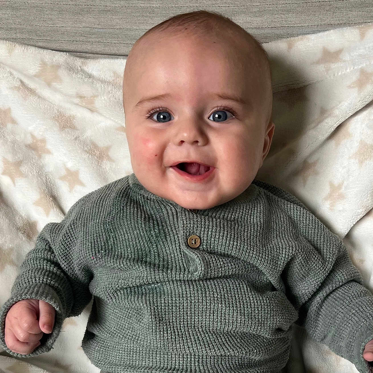 Raphaël participe au concours pour gagner de l'argent avec cette photo : baby, blanket, blue_eyes, child, closeup, cozy, cute, face, green_sweater, happy, indoor, infant, knit_sweater, person, plush_blanket, portrait, sitting, smiling, star_pattern, warm_clothing