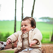Elyass participe au concours pour gagner de l'argent avec cette photo : baby, child, smiling, outdoor, nature, greenery, trees, blanket, clothing, happy, person, portrait, jacket, pants, footwear, hand, face, sitting, infant, warm