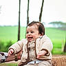 baby, child, smiling, outdoor, nature, greenery, trees, blanket, clothing, happy, person, portrait, jacket, pants, footwear, hand, face, sitting, infant, warm