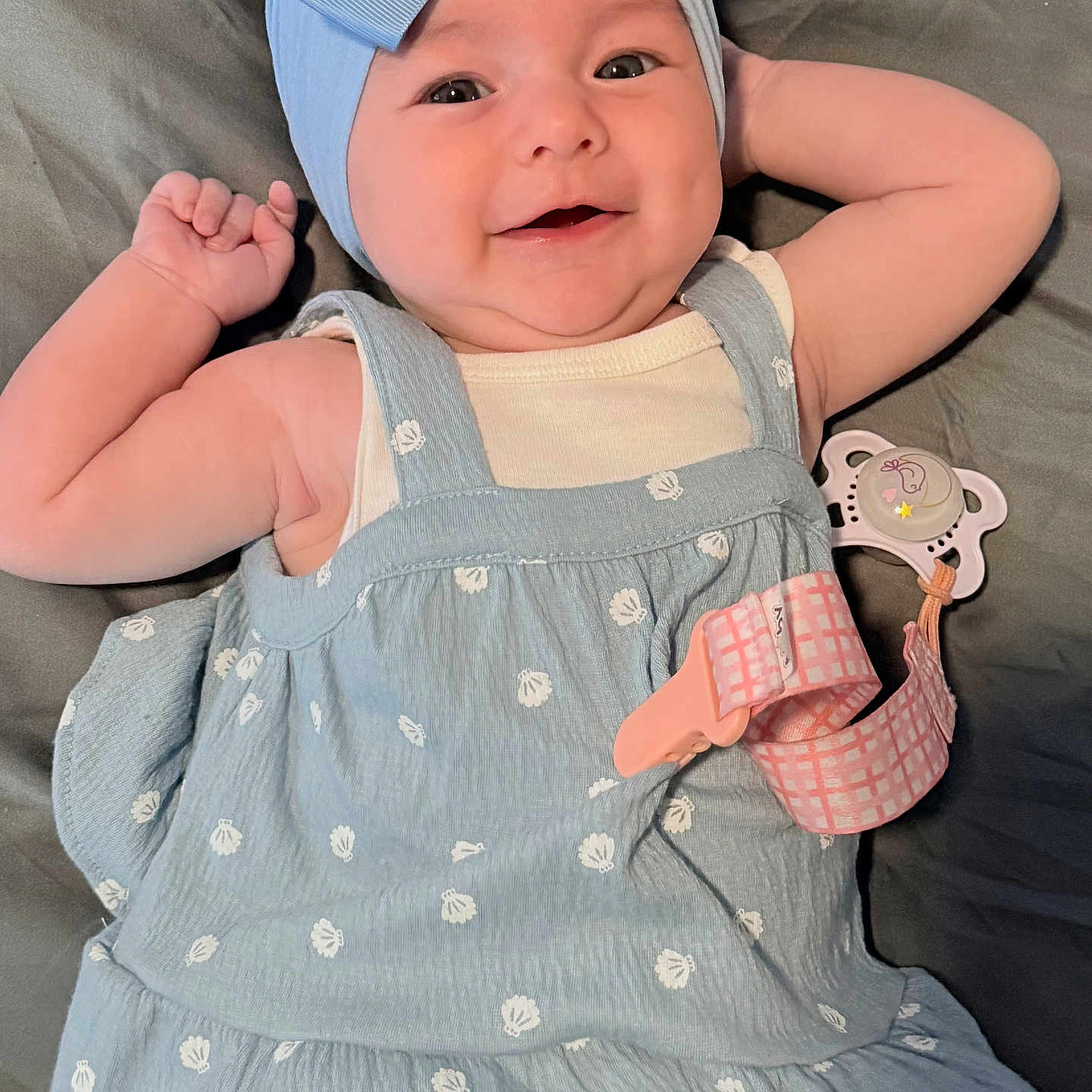 Salem joined the competition — help win amazing prizes! arm, baby, blanket, blue_bow, child, clothing, cute, dress, face, hand, happy, headwear, indoors, infant, lying_down, pacifier_clip, portrait, skin, smile, wearing